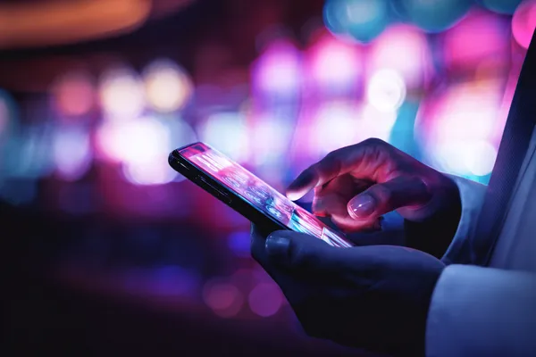 A woman smiling by bright slot machines showing lucky symbols, showcasing the exciting slot offerings at OKTKK.